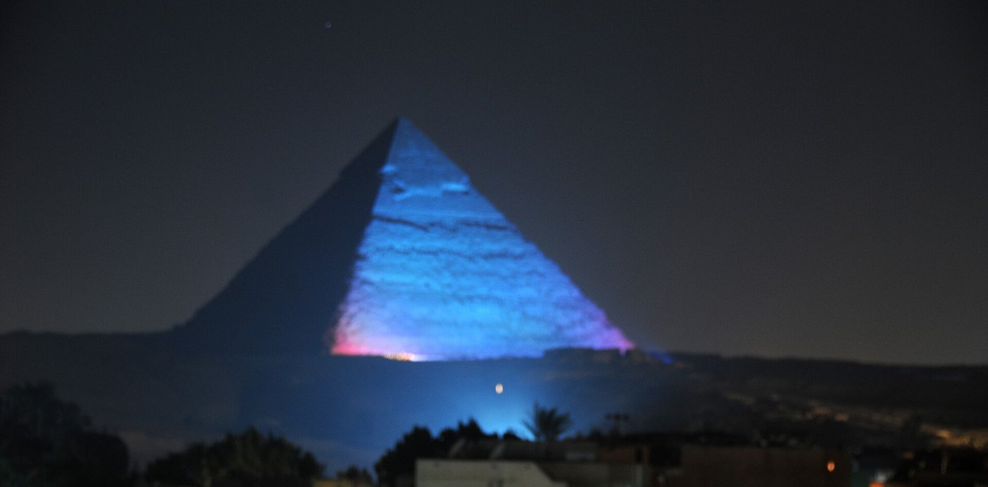 A Giza pyramid lit up blue against the night sky